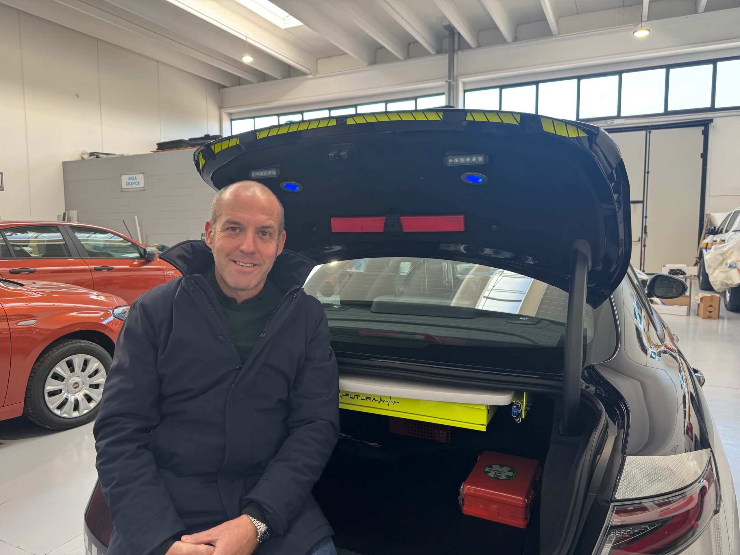 Stefano Robotti showcasing the integrated LED lighting system in the trunk lid of a police vehicle